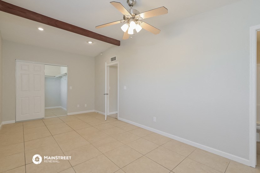 the spacious living room with ceiling fan and tiled floor