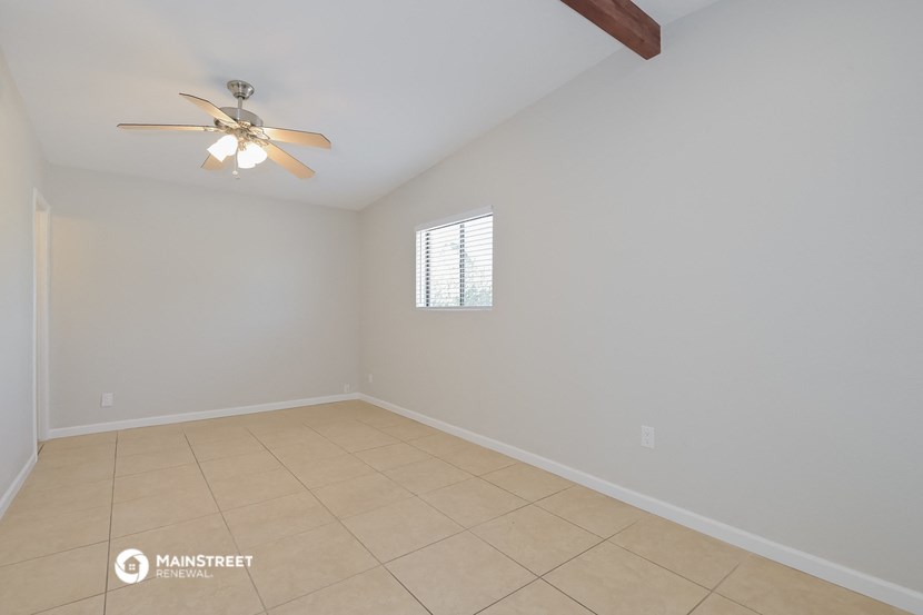 the spacious living room with ceiling fan and tiled floor