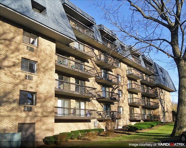 a brick apartment building with balconies and a tree