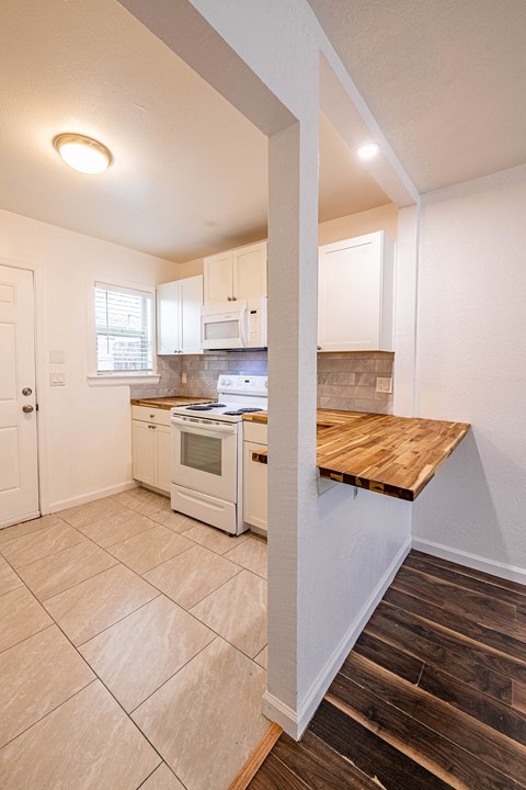 a kitchen with white appliances and a wooden counter top