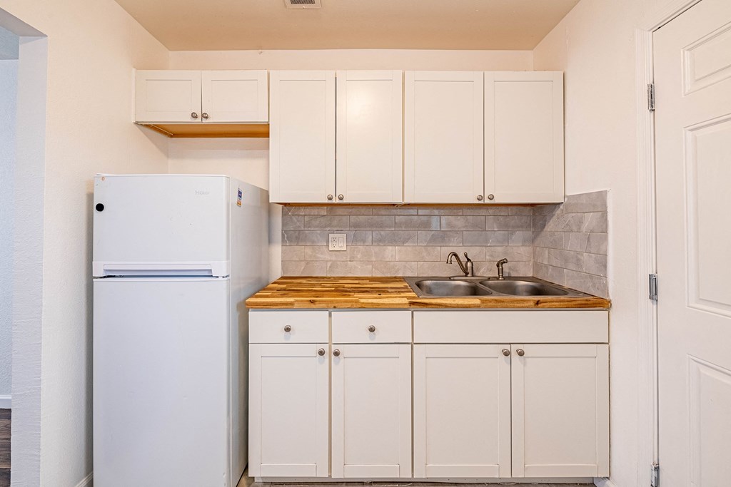 a small kitchen with white cabinets and a refrigerator