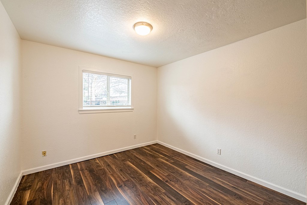 an empty room with wood flooring and a window