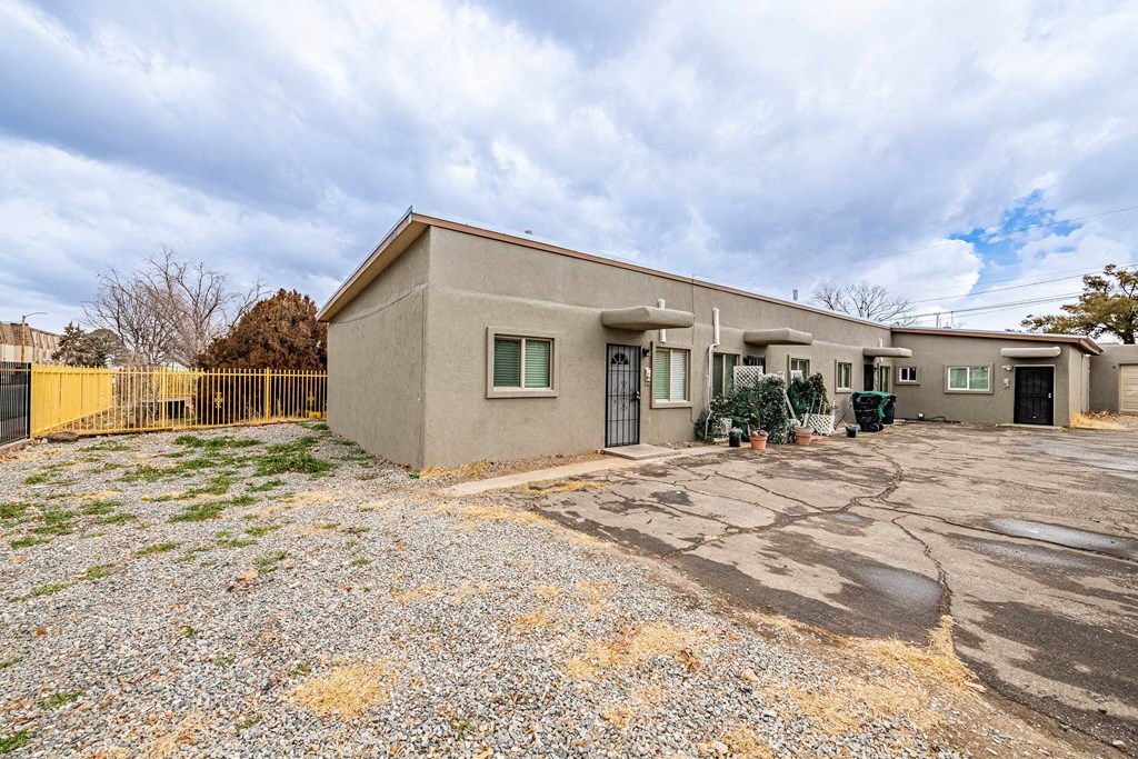 a beige house with an empty lot and a driveway