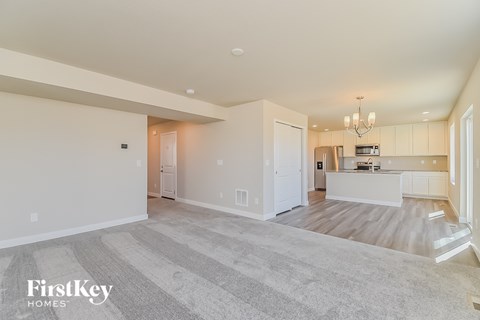 A spacious living room with a kitchen in the background.