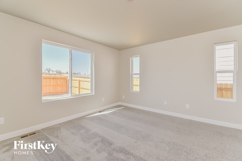 A room with a carpet floor and two windows.