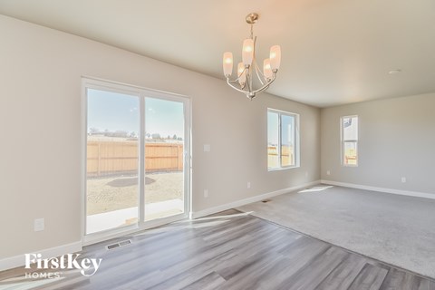 A spacious room with a chandelier and a view of a fence and trees outside the window.