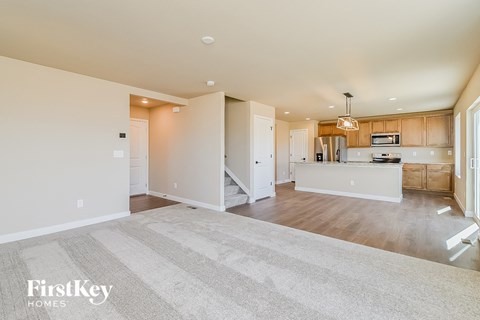 A spacious kitchen and living room with a striped rug on the floor.