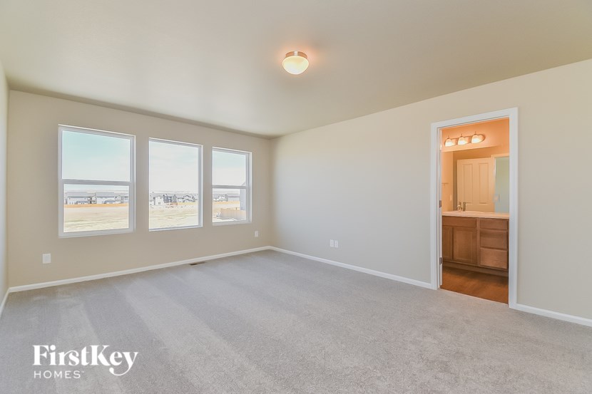 A spacious room with a carpeted floor and a view of the outside through the windows.