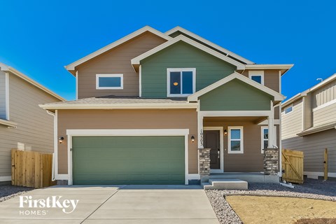 a green and brown house with a garage door