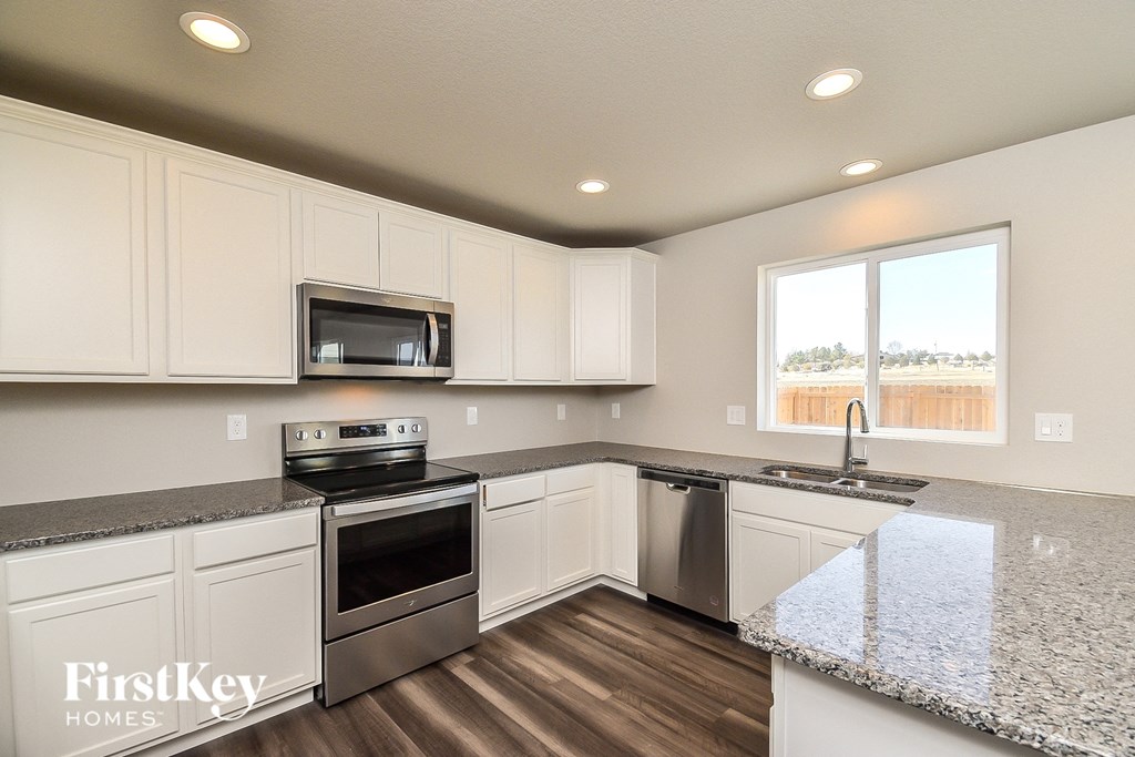 a kitchen with white cabinets and granite counter tops and stainless steel appliances