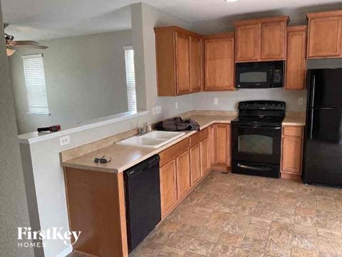 A kitchen with wooden cabinets and black appliances.