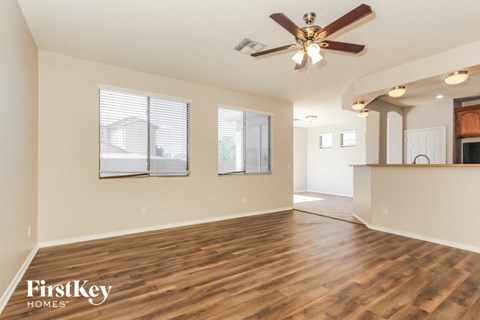 an empty living room with a ceiling fan and a kitchen