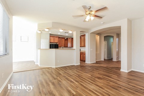 a living room and kitchen with wood flooring and a ceiling fan