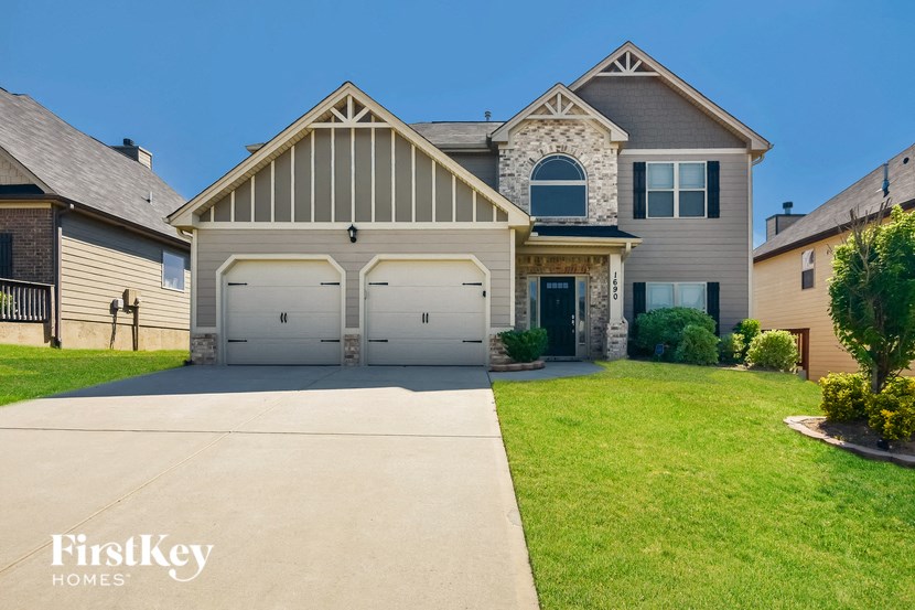 a large house with two garage doors on a driveway
