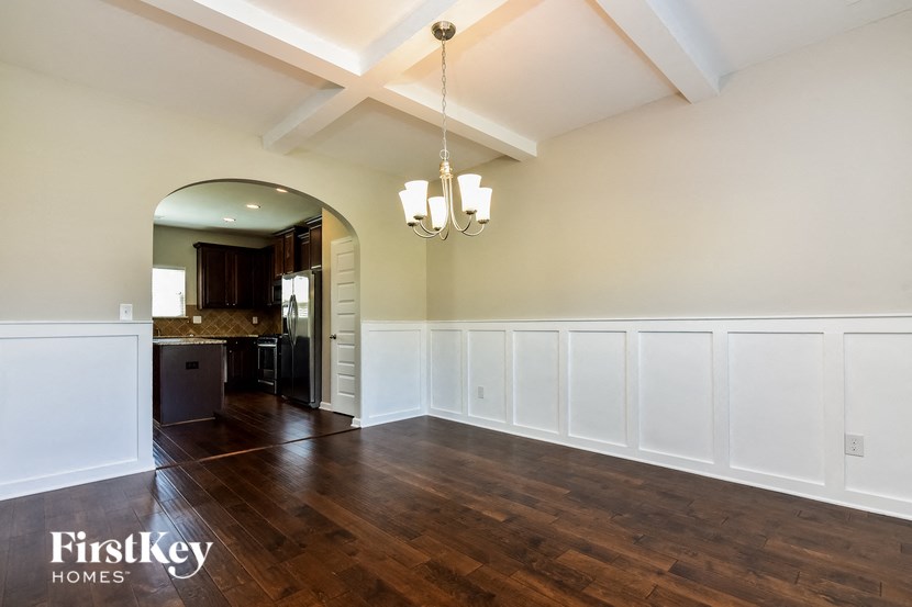 a dining room with white wainscoting and a door to the kitchen