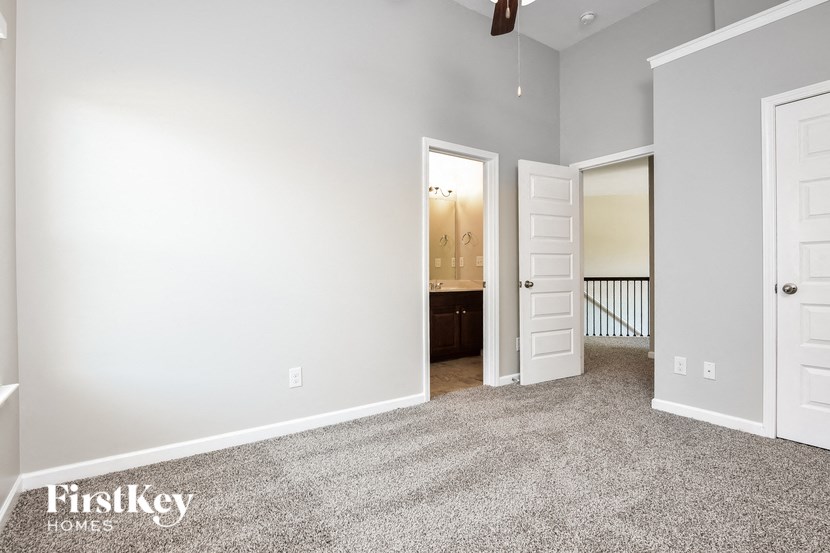 a bedroom with a carpeted floor and a door to a bathroom