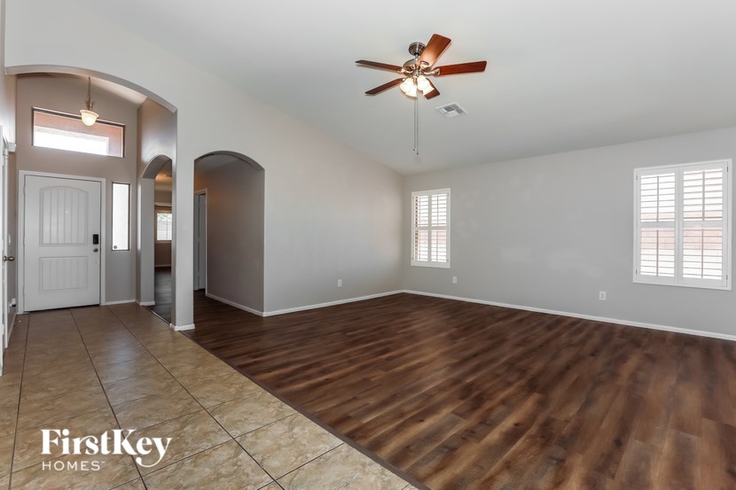 A spacious room with wooden floors and a ceiling fan.