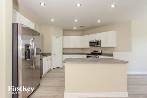 A kitchen with a stainless steel refrigerator and a countertop with a microwave on it.