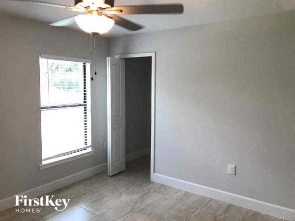 an empty living room with a ceiling fan and a window