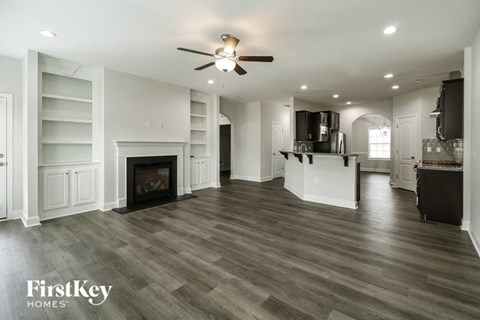 A spacious living room with a fireplace and a ceiling fan.