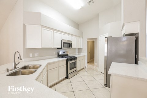 A kitchen with white cabinets and a stainless steel refrigerator.