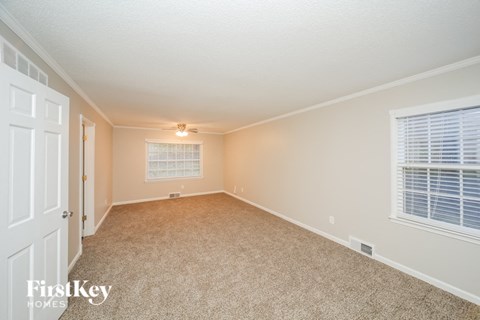 a spacious living room with beige carpet and a white door