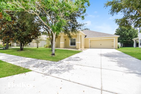 a white driveway in front of a yellow house