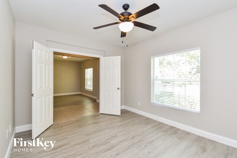 a living room with a ceiling fan and a door to a hallway