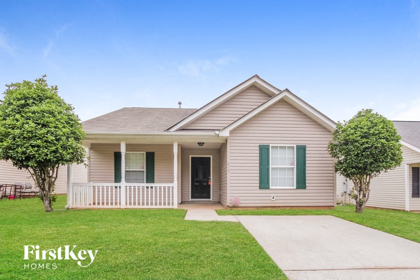 a house with green shutters and a sidewalk in front of it