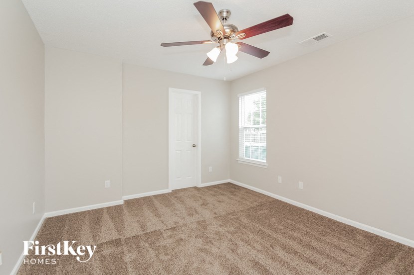 an empty living room with a ceiling fan