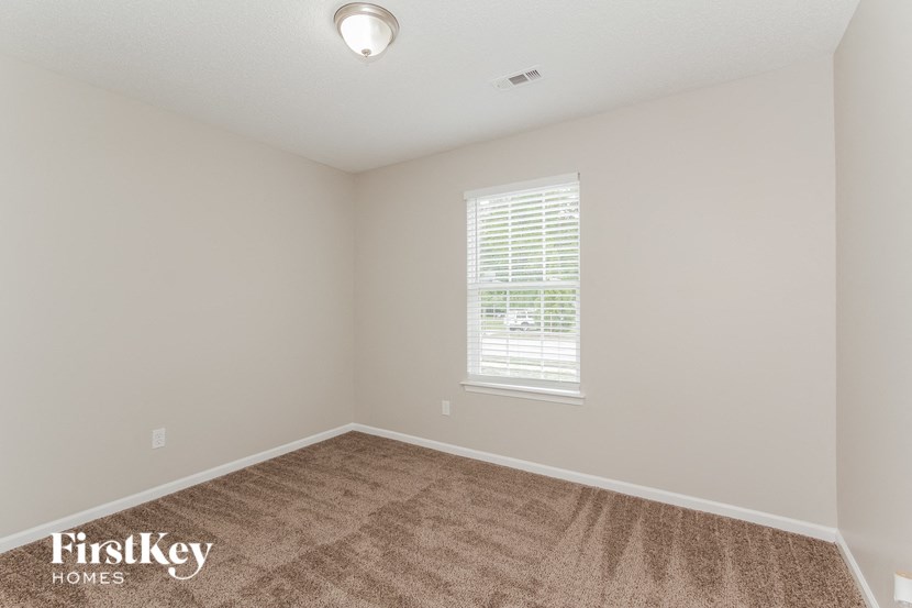 a bedroom with a carpeted floor and a window