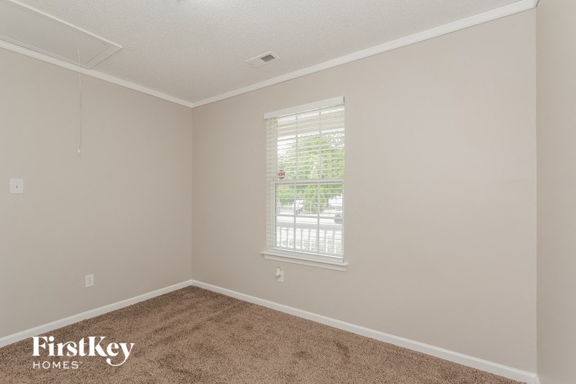 the bedroom of a home with carpet and a window