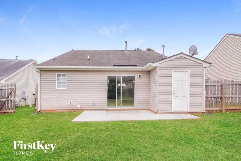 a small tan house with a yard and a wooden fence
