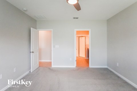 a bedroom with a carpeted floor and a door to a bathroom