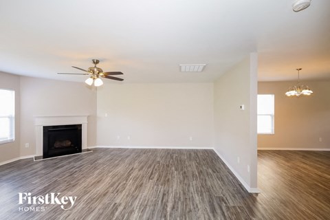 A spacious living room with a fireplace and wood flooring.
