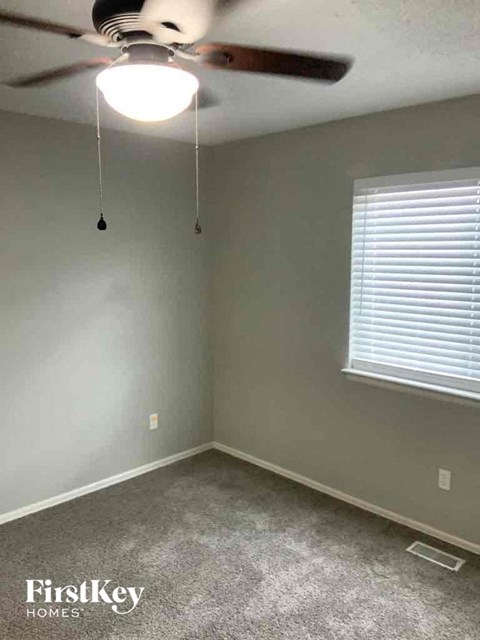 an empty room with a ceiling fan and a window