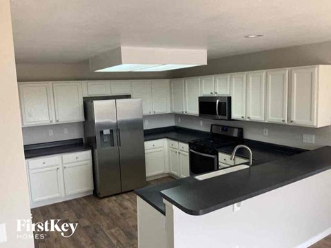 a kitchen with white cabinets and a stainless steel refrigerator