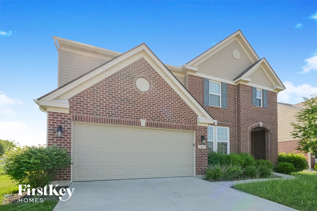 A brick house with a garage door and a sign that says "FirstKey Homes".