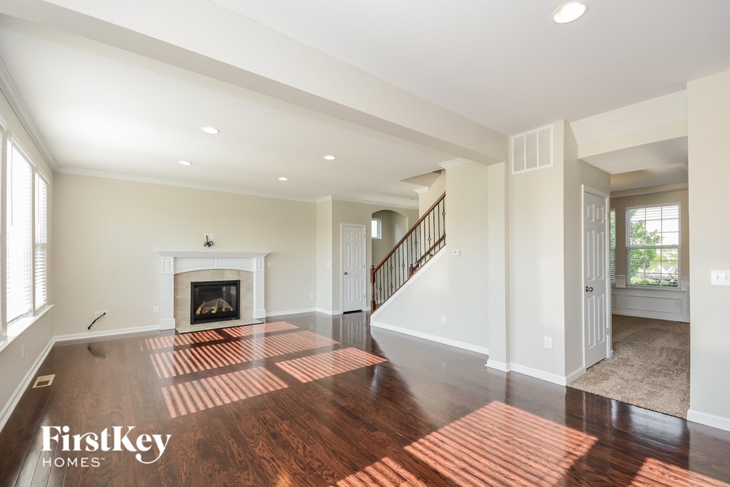 A spacious living room with a fireplace and a staircase.