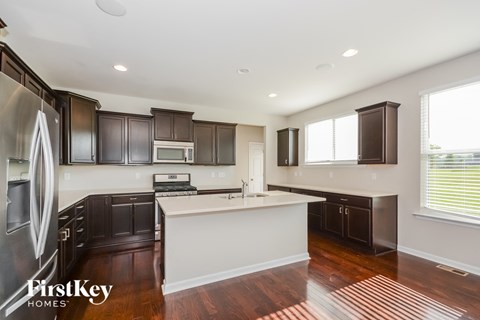 A kitchen with dark wood cabinets and a white island.