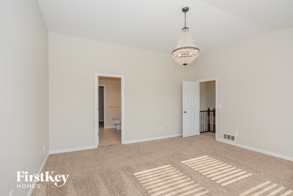 A spacious room with a carpeted floor and a chandelier hanging from the ceiling.