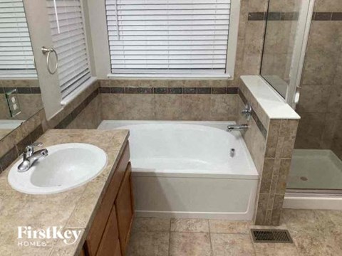 A bathroom with a tub, sink, and window.