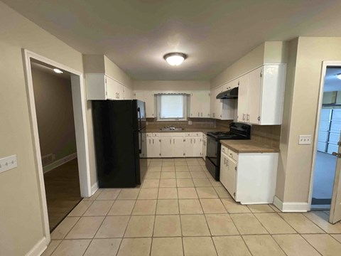 A kitchen with black and white appliances and tiled flooring.