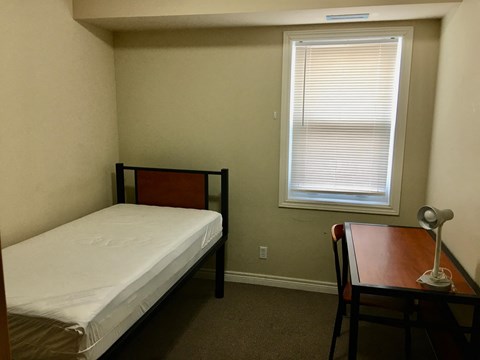a small bedroom with a bed and a desk and a window