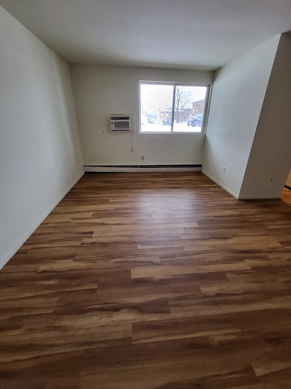 an empty room with wooden floors and a window