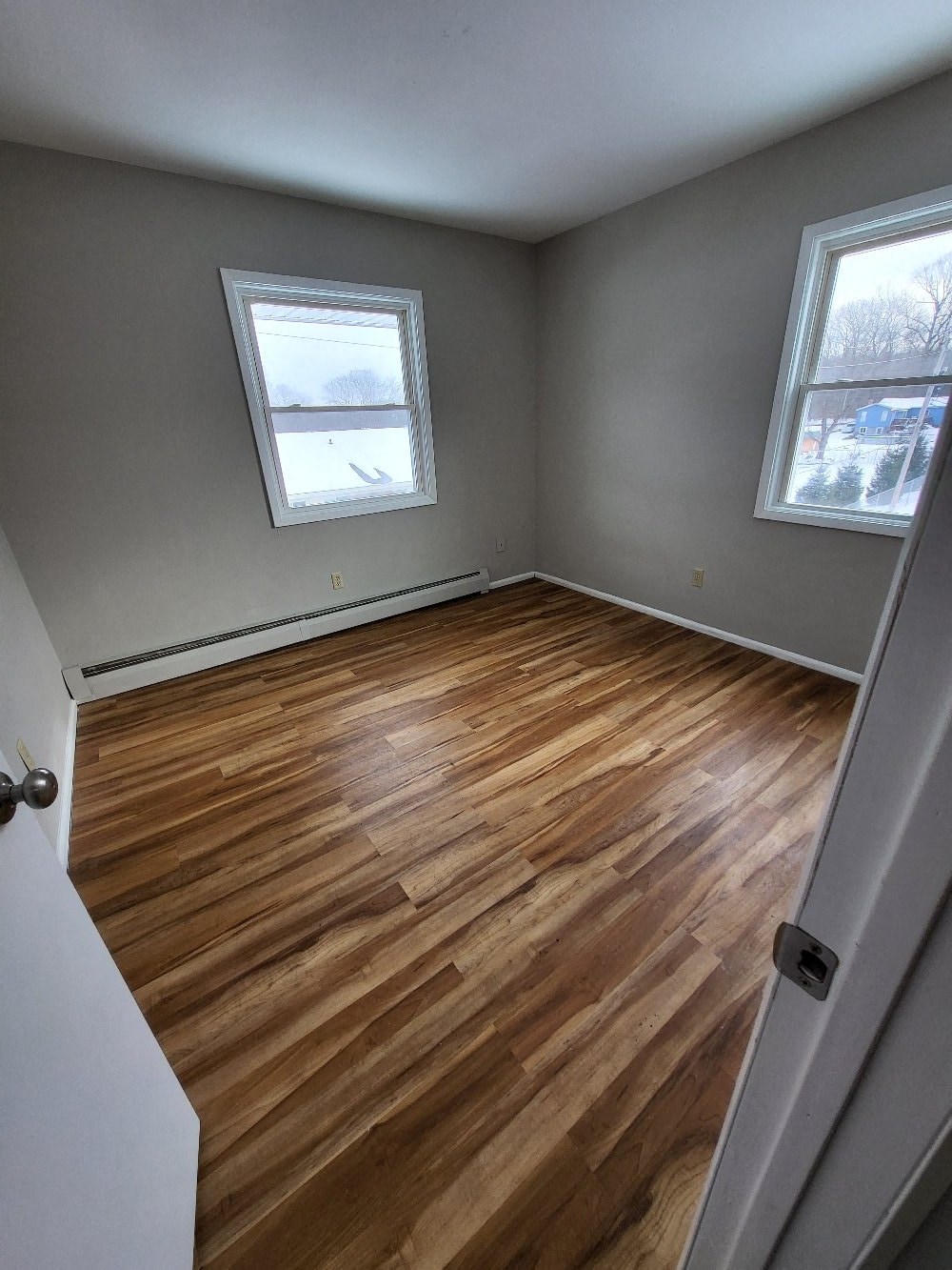 a room with wooden floors and two windows