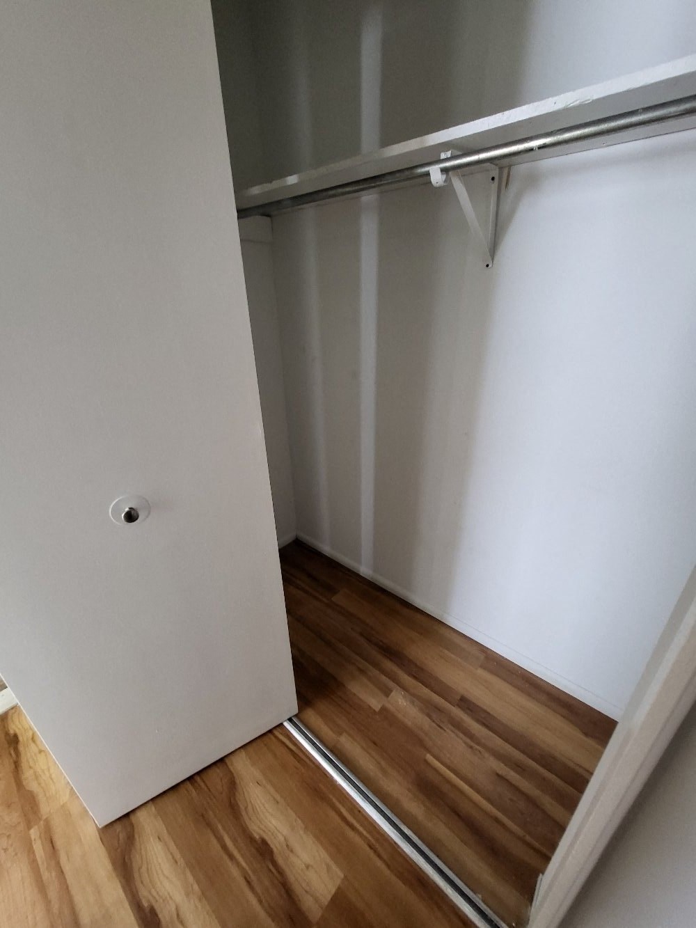 a walk in closet with a sliding door and wooden floors