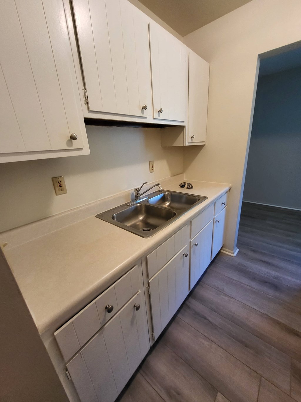 an empty kitchen with white cabinets and a sink