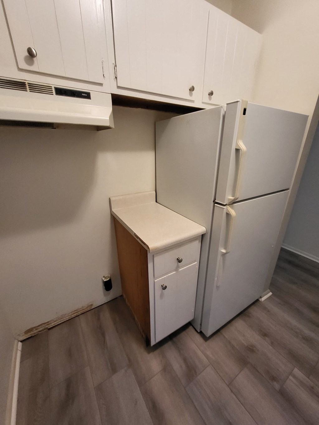 an empty kitchen with a refrigerator and a small cabinet