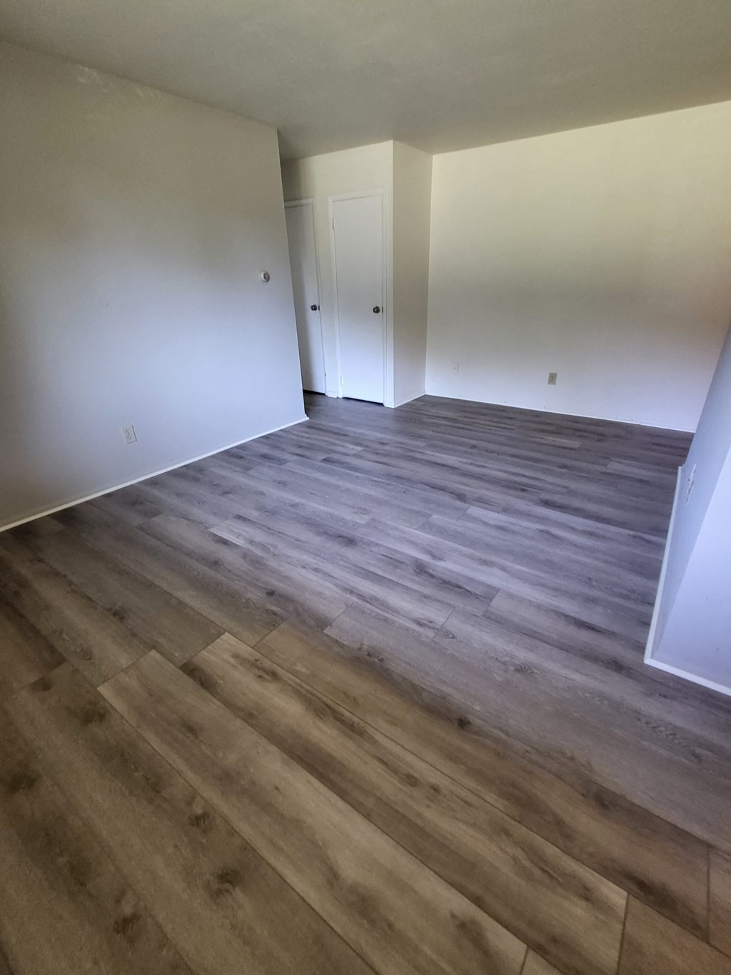 the living room of an empty house with wood flooring
